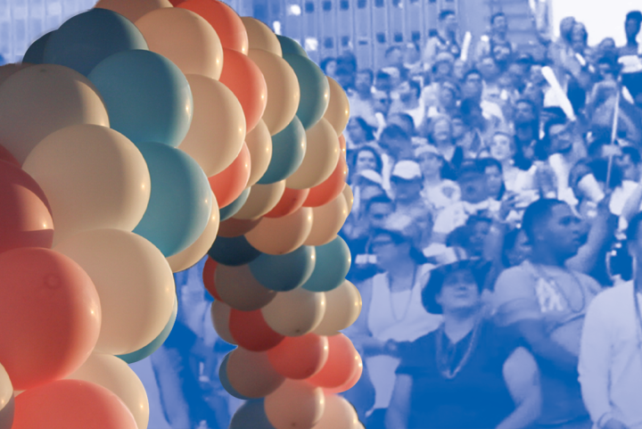 Trans Awareness Week Image: An image of balloon arch with alternating trans pride colors overlaps a stylized image of a crowd of people gathered.