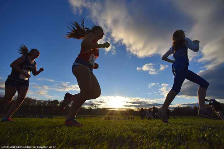 Several silhouettes of individuals running track.