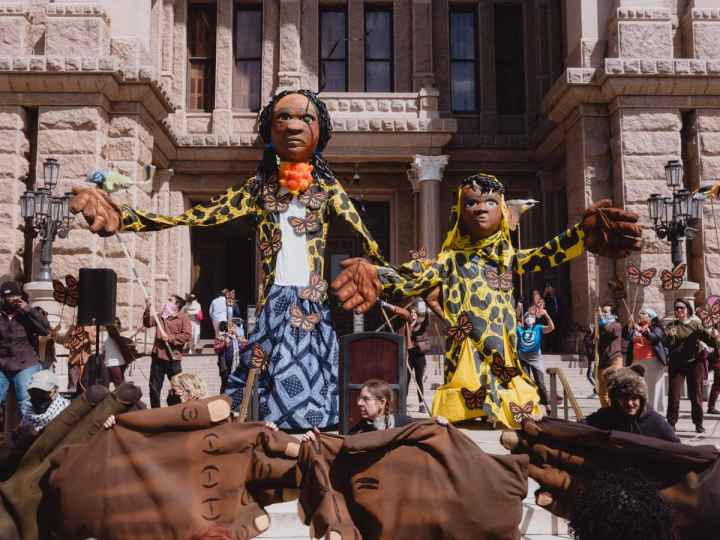 Two giant puppets greet attendees at an immigrants' rights rally