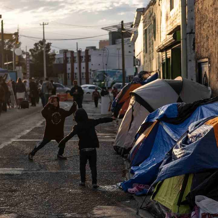 Two boys running around and playing outside of tents in Ciudad Juarez, Mexico.