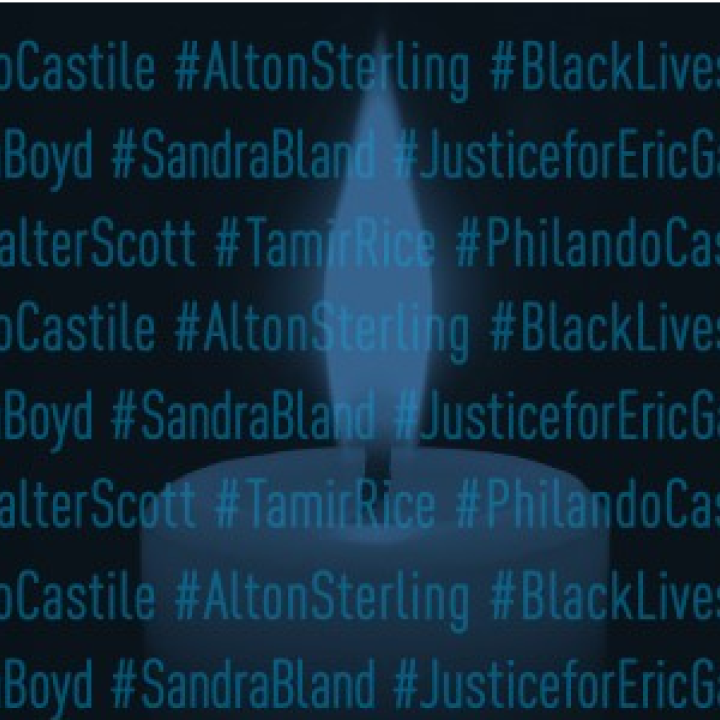 Candle burning behind hashtagged names of victims of police shootings