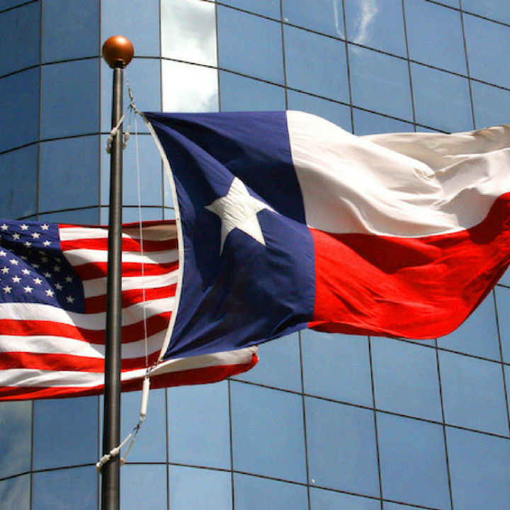 TexasandAmericanFlag Photo: A Texas and United States flag wave in the wind on two separate flagpoles in front of a corporate building.